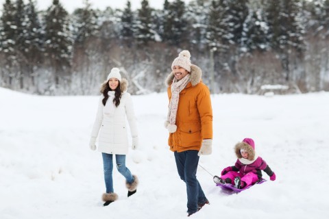 happy family with sled walking in winter forest